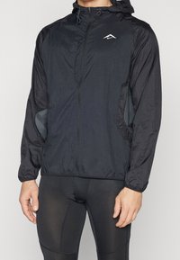 Czarna, lekka kurtka przeciwdeszczowa z zamkiem błyskawicznym, kapturem i bocznymi kieszeniami; charakteryzuje się teksturowanym materiałem oraz małym logo na piersi.