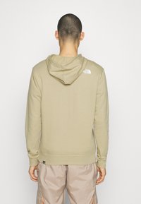 Felpa khaki con design aderente, maniche lunghe e cappuccio con coulisse. Presenta un piccolo logo bianco sulla parte superiore della schiena. Tessuto morbido.