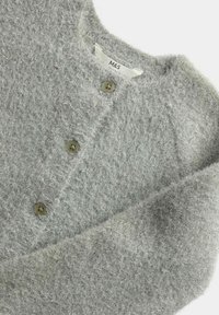 Jasnoszary, puszysty kardigan o fakturowanej powierzchni, z pięcioma brązowymi guzikami i okrągłym dekoltem. Metka brzmi "M&S."