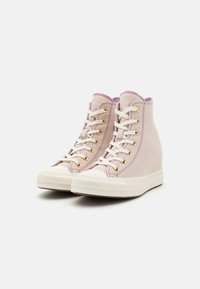 High-top sneakers in light pink canvas with gold eyelets, white laces, and textured soles. Accented with a contrasting darker pink collar.