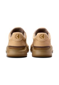 Beiga sneakers med ett slätt läderöverdrag, vadderad krage och texturerad gummisula. Har en cirkulär logotyp och bruna detaljer på hälen.