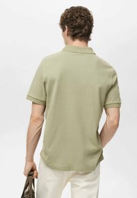 Khaki polo tričko s krátkým rukávem a čistým designem s texturovaným povrchem. Má klasický límeček a větrací otvor na zádech.