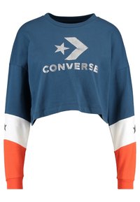 Zkrácená modrá bavlněná mikina s stříbrným logem "CONVERSE", která má dlouhé rukávy v bílé a oranžové barvě s hvězdným vzorem.