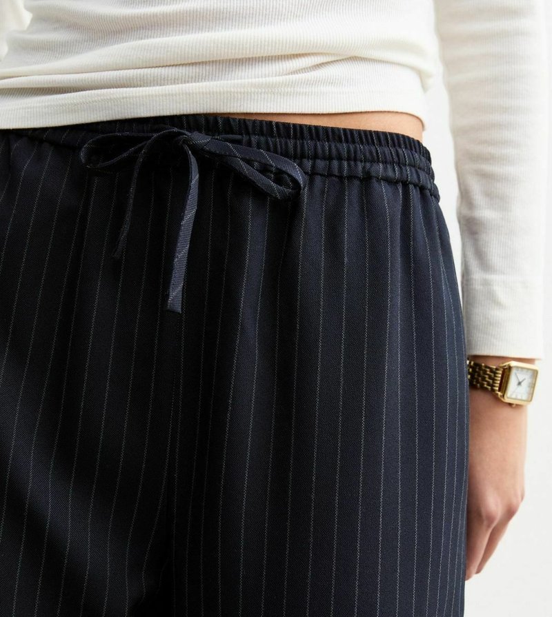 Pantaloni a righe blu navy con vita regolabile, caratterizzati da righe verticali, tessuto testurizzato e vestibilità morbida.