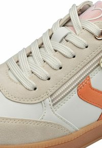 Beige and white sneaker with a suede upper, textured rubber sole, orange accent, and woven laces. Features a side zipper detail.