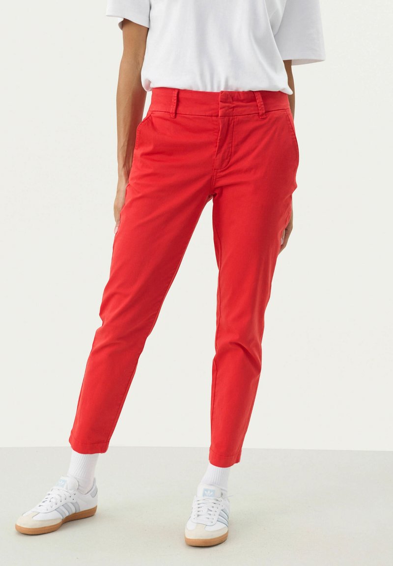 Rode katoenen chino's met een rechte pasvorm, voorzien van zijzakken, een tailleband met lussen en opgerolde broekspijpen, in combinatie met witte sneakers.