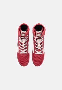 Κόκκινα ψηλά αθλητικά παπούτσια με λευκά κορδόνια και λεπτομέρειες, επάνω μέρος από δίχτυ, και λογότυπο φιδιού στη γλώσσα, σε θέα από πάνω σε λευκό φόντο.