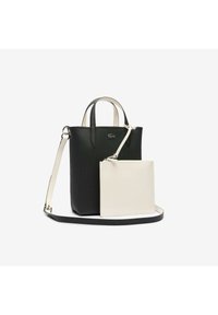 Sac cabas en cuir noir avec des poignées courtes et une longue bandoulière, accompagné d'une petite pochette blanche détachable fixée par une lanière de poignet.