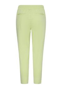 Pantalon vert clair fuselé avec ceinture élastique et deux poches à passepoil à l'arrière, présenté de dos sur un fond blanc uni.