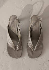 Light gray slingback sandals with a knotted front design. Made of soft material, featuring flat soles and textured insoles.