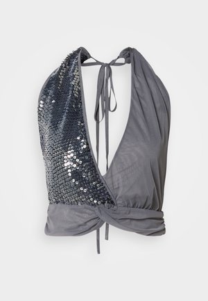 Halter-neck top in grey fabric with a deep V-cut. One side features dark sequins, while the other is smooth with a tied back detail.