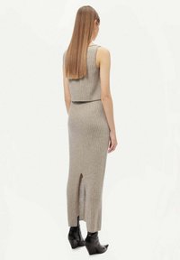 Grått ribbat set i två delar som inkluderar en ärmlös crop top och en lång kjol med en slits bak. Bärs med svarta klackstövlar.