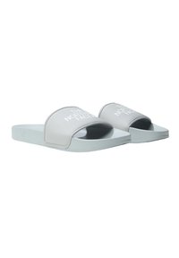 Chanclas con suela de goma de color gris claro, que cuentan con una amplia correa superior suave. La correa tiene una marca impresa en blanco.