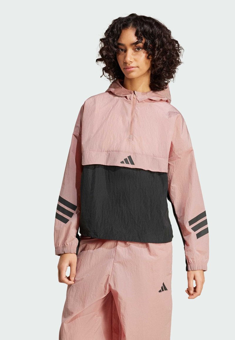 Lätt, färgblockerat vindskydd med rosa överdel och svart bröst, med nedhängande axlar, huva och tre svarta ränder på ärmarna.