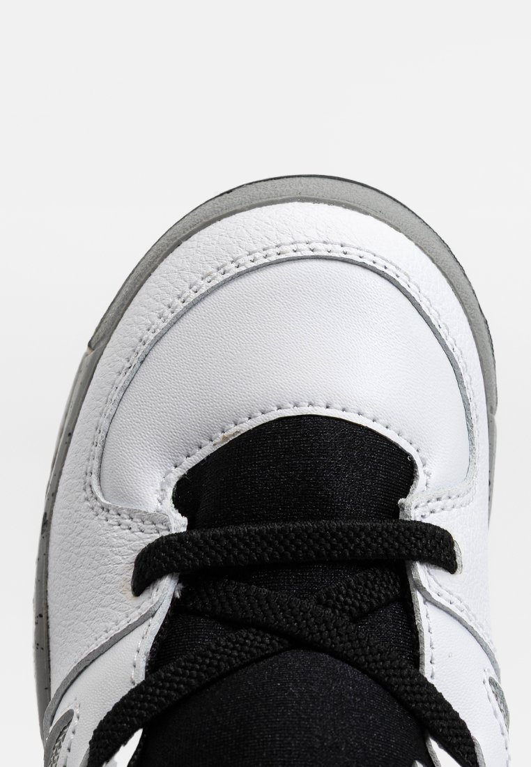Witte leren sneaker met zwarte stoffen tong en veters, grijze rubberen zool en een gestructureerde bovenkant met stiksel details.
