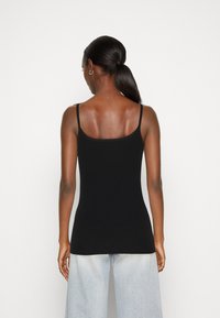 Svart fitted cami med tunna remmar, tillverkad av ett mjukt, slätt tyg. Bakdelen är enfärgad och designad för en åtsittande passform.