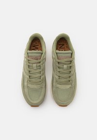 Zielone płótniowe trampki z teksturowanymi nakładkami, okrągłym noskiem i wyściełaną korkową wkładką. Posiadają klasyczne sznurowanie i gumową podeszwę.