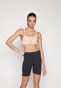 Lyserosa sports-bh med mesh-paneler og mørke detaljer, kombinert med svarte høyde-wrist sykkelshorts, begge laget av elastisk stoff.