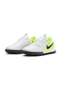 Des chaussures de sport blanches avec un dessus texturé, des accents verts et une virgule noire. Elles possèdent une semelle en caoutchouc pour une meilleure adhérence.