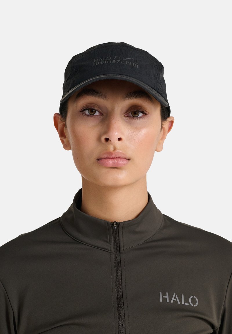 Czarna czapka z daszkiem z wytłoczonym logo "HALO". Osoba nosi również ciemnoszary, zapinany na zamek sweter o gładkiej fakturze i minimalistycznym designie.
