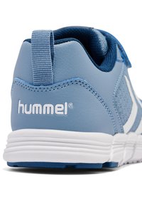 Blå sportskor med en slät läderöverdel, nätdetaljer och vita accenter. Har en dragflik och en texturerad gummisula. Logotyp närvarande.