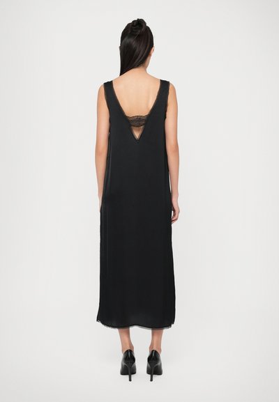 Black sleeveless dress with a V-shaped back, lace accent, and straight cut. Made of soft fabric with a flowing design and subtle hem.