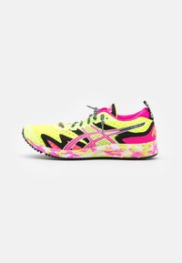 Chaussure de sport avec un dessus en mesh jaune, des accents roses et noirs, des détails réfléchissants et une semelle texturée arborant un motif multicolore vif.