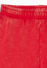 Pantalones de chándal rojos con cintura elástica y una tela suave y texturizada. El diseño es simple, sin patrones ni acentos adicionales.