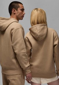 Felpe color khaki realizzate in tessuto morbido, con una vestibilità comoda, grandi cappucci e polsini a costine. Una felpa ha una tasca frontale.