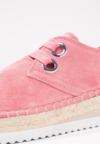 Baskets en daim rose avec œillets en argent ronds, lacets tressés roses et semelle enroulée de jute. Comprend une semelle extérieure en caoutchouc blanc avec un motif ondulé.