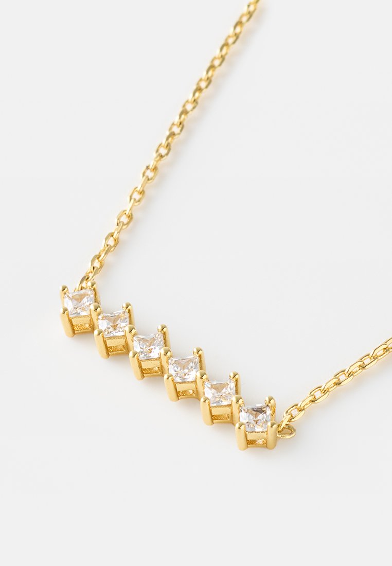Collana d'oro con cinque cristalli trasparenti tagliati a squadrato, fissati con prong, collegati da una delicata catena. Texture liscia con finitura lucida.