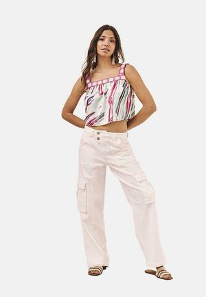 Top sin mangas, recortado, con rayas multicolores y ribete rosa, combinado con pantalones cargo blancos que tienen bolsillos laterales y un corte holgado.