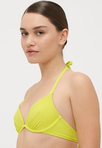 Neon grønn bikini topp med trekantet design, justerbar halterneck-knute og frontknutepunkt; glatt tekstur og minimal maskinvare.