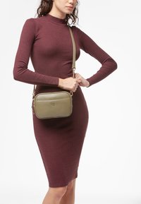 Borsa a tracolla verde oliva realizzata in pelle texturizzata con chiusura a zip, dotata di una tracolla removibile e decorazione con logo.