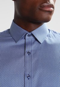 Blauw overhemd met een geometrisch patroon van cirkelvormen, een klassieke kraag en knoopsluiting, gemaakt van een gladde, ademende stof.