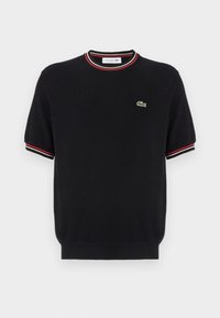 Black knitted short-sleeve sweater with a round neck, featuring red and white stripe accents on the collar and sleeves, and a small green logo.