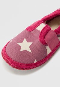 Violeta auduma čīpas ar baltu zvaigžņu rakstu, rozā apdari un Velcro siksnu. Mīksta tekstūra un noapaļota forma ir izstrādāta komfortam.