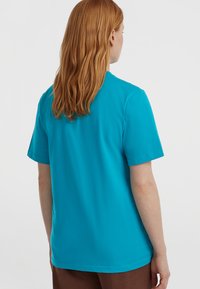 Türkise lühikeste sleeves'iga t-särk sirge lõikega, lihtsa disaini ja siledaks tekstuuriga, nähtud tagasi vaates ümmarguse kaelusega.