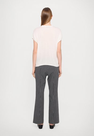 White, short-sleeved top paired with black and white plaid trousers, featuring a flared leg cut. Smooth fabric, minimalistic design, and subtle texture.