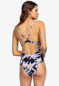 Eén-delig zwemoutfit met een marineblauw bloemenpatroon met roze en blauwe lelies; crisscross bandjes en een uitgesneden achterkant.