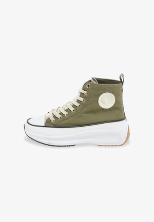 Hoge sneakers van olijfgroen canvas met een witte rubberen neuskap, contrasterende zwarte rand, beige zool en een ronde logo sticker aan de zijkant.