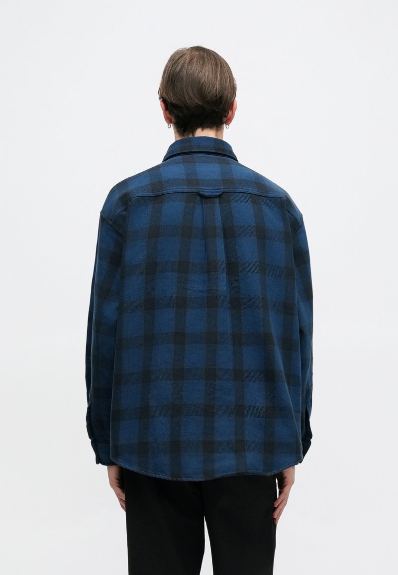 Blauwe en zwarte geruite flanellen shirt met een kraag, lange mouwen en een ronde zoom, voorzien van een zachte stoftextuur en een rugpasdetail.