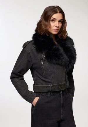 Giacca di denim nera con ampio colletto in pelliccia sintetica, vita con cintura e tasche con zip. Presenta cuciture robuste e una vestibilità leggermente oversize.