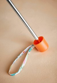 Metalstang med en skinnende sølvfinish, sikret i en orange plastbund; har en stofsløjfe med blomsterdesign fastgjort.