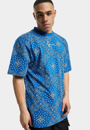 T-shirt bleu à manches courtes avec un motif paisley, featuring des accents blancs et un col rond. Fabriqué en tissu léger, coupe décontractée.