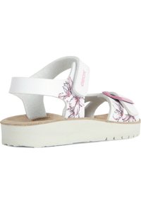 Sandalias Geox blancas con diseño floral, tira ajustable, parte superior perforada y suela de plataforma de color claro y textura.
