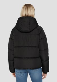 Sort pufferjakke med hætte, der har et quiltet design, elastiske manchetter og en let cropped pasform. Baggudsigt viser horisontale syninger.