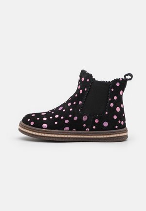 Bottine en daim noir à pois roses, panneau latéral élastique, languette de tirage et semelle marron cousue.