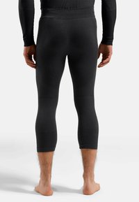 Schwarze Kompressionsleggings mit gerippter Textur, knöchelfreier Länge und nahtlosem Taillenbund. Die Füße sind barfuß und zeigen ein sauberes Design.
