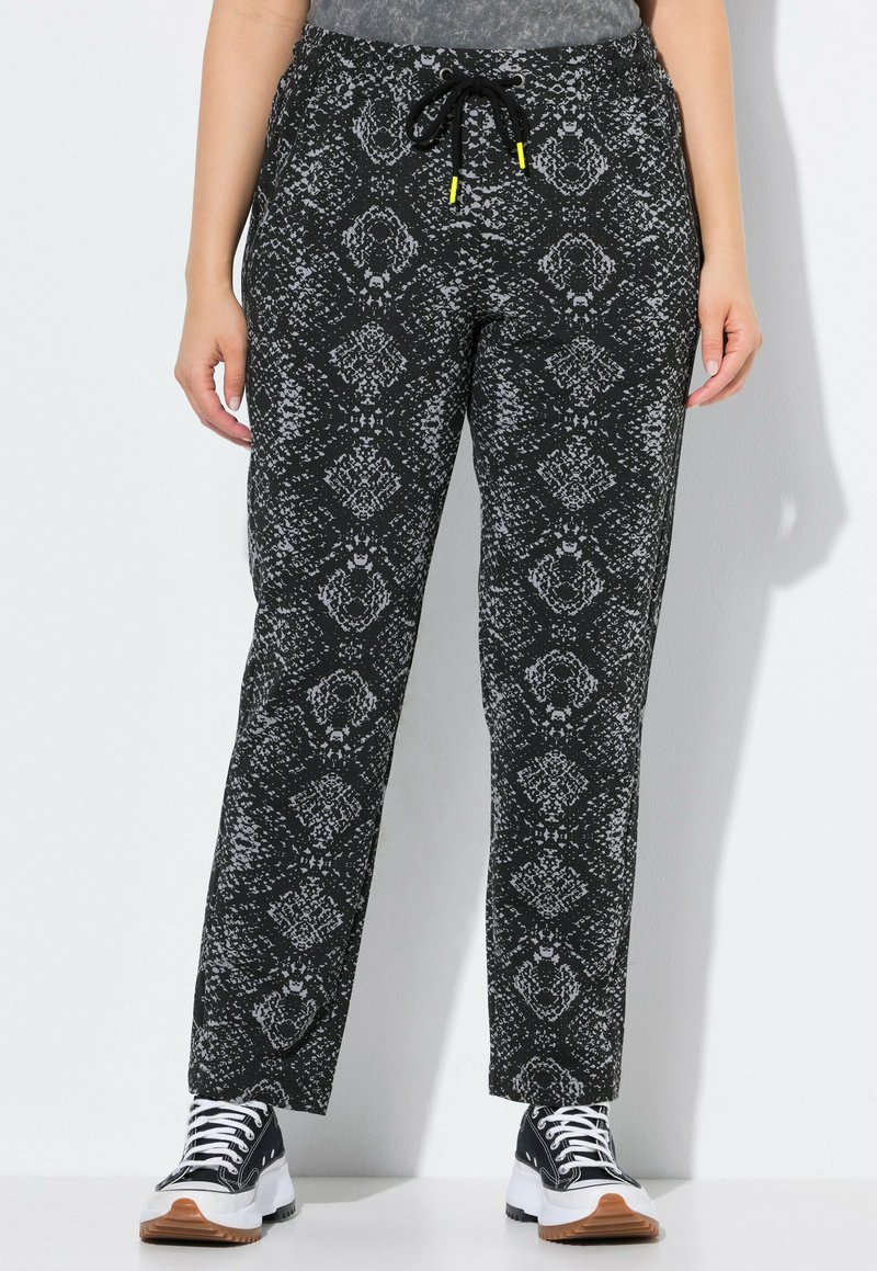 Pantalons noirs avec un motif texturé serpent en gris. Dotés d'une taille à cordon coulissant, d'une coupe ample et portés avec des baskets noir et blanc.